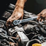 mani di un meccanico a lavoro nel cofano di un'auto
