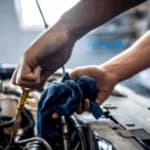 mani di un meccanico a lavoro nel cofano di un'auto