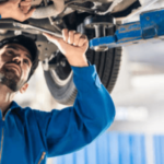 meccanico al lavoro sotto un auto